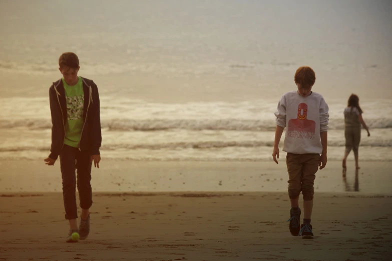 two boys on the beach look at the waves