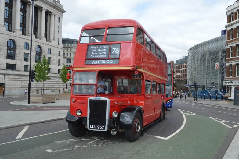 a red double decker bus driving down a street