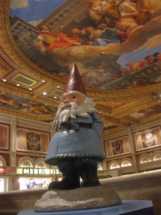 a statue in a large ornate room under a painting