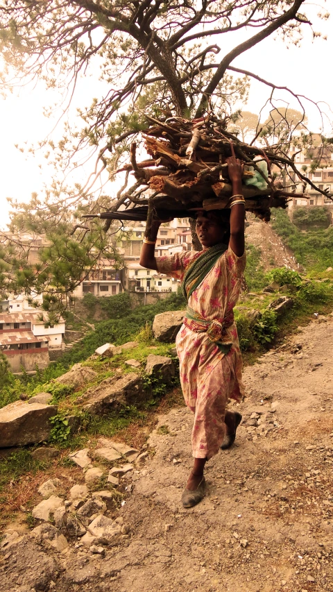 a woman carrying soing on her head over a hill