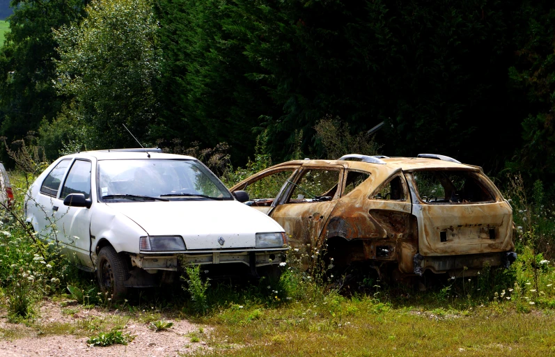 there are two broken cars and one is white