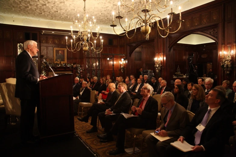 people sitting in a room and a man speaking from a podium