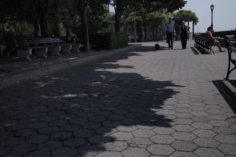 people walk along the path by some benches