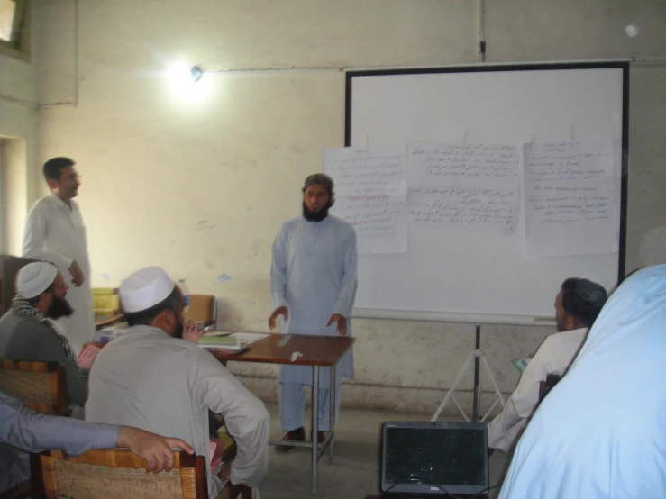 there are several men in front of a whiteboard