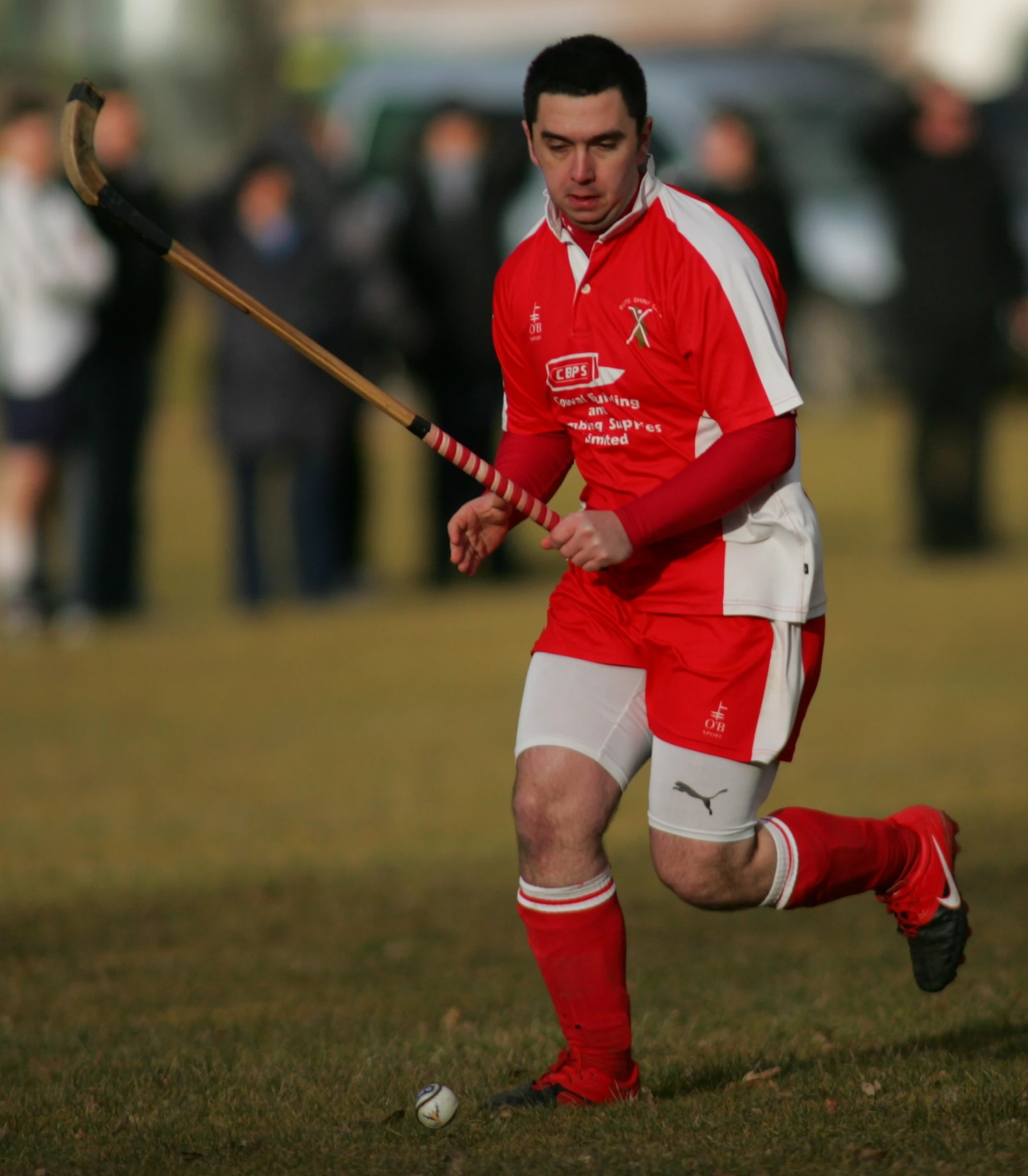 a young male in red uniform running with a stick