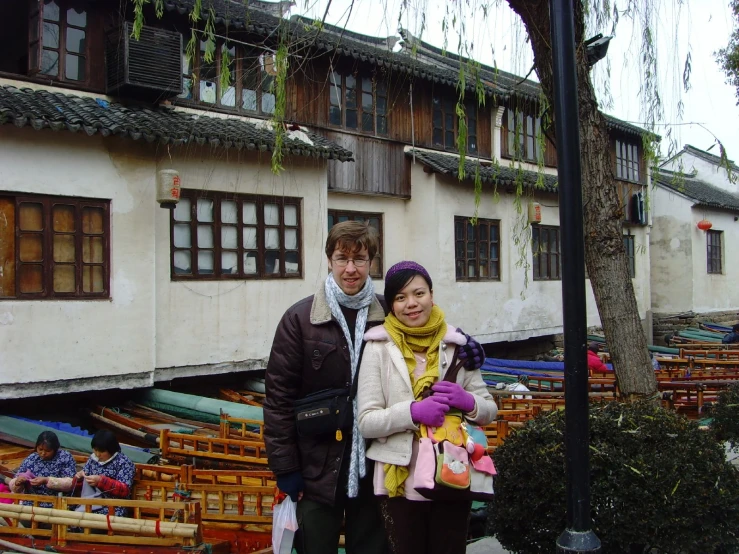 a couple stand together in front of a building