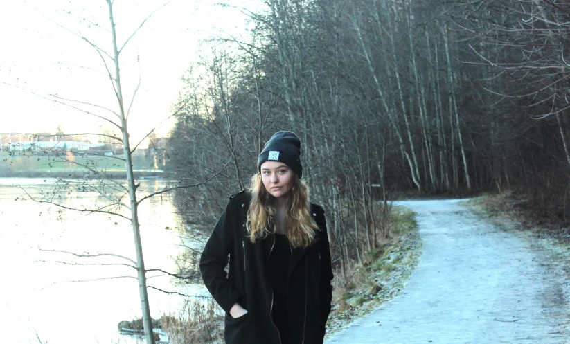 a girl in a black jacket is on a dirt road