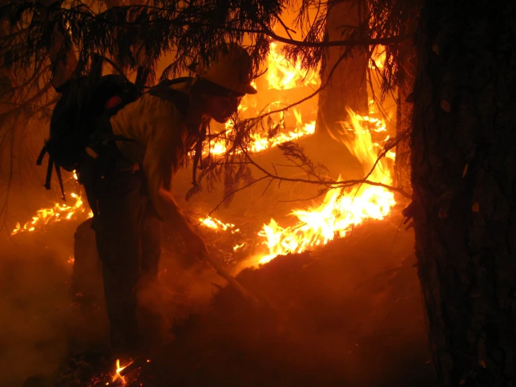 a fire fighter in the dark of night using a hose