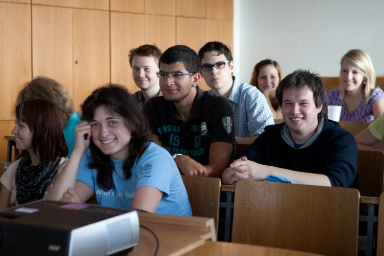 a group of people sitting at tables in classroom next to each other