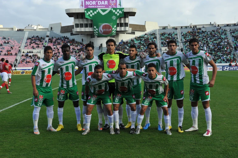 a group of men in green uniforms stand on the soccer field