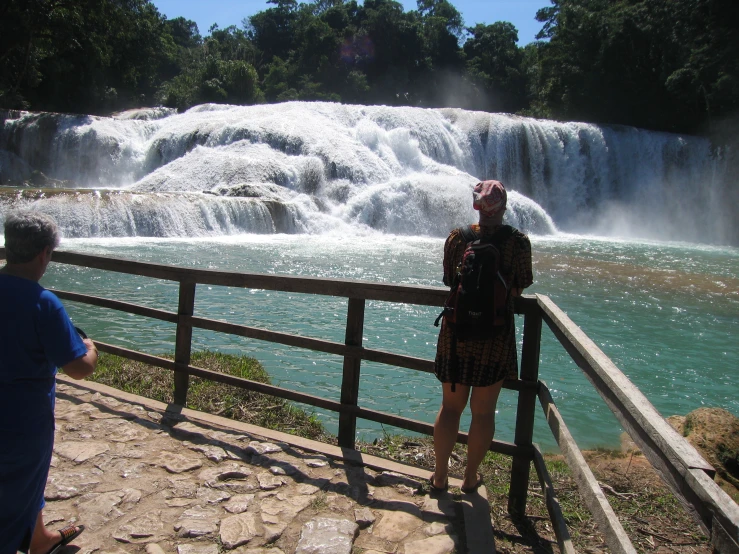 a couple looking at a waterfall while a man takes a picture