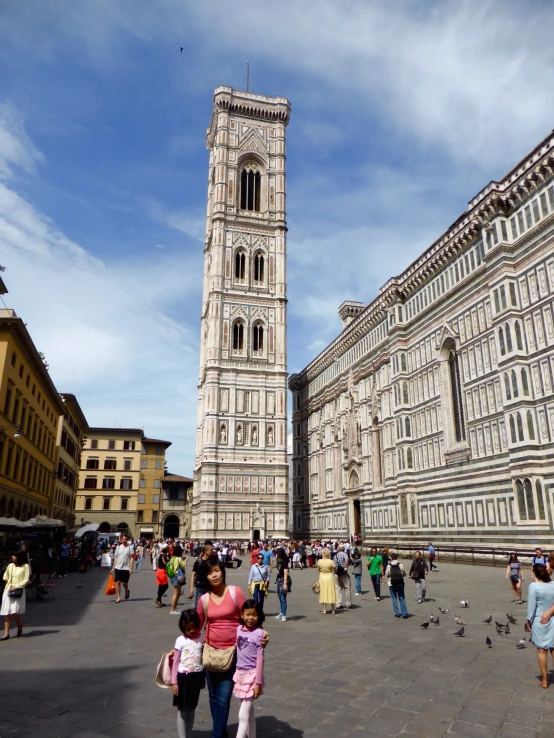 people walk around an area with a large stone tower