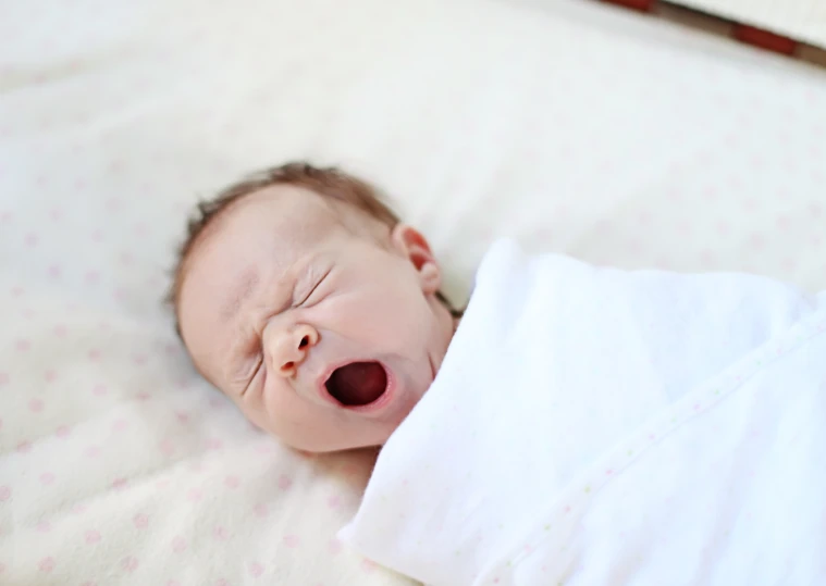 a newborn baby laying on a white sheet