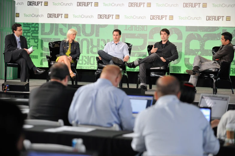 a group of people sit around on stage talking