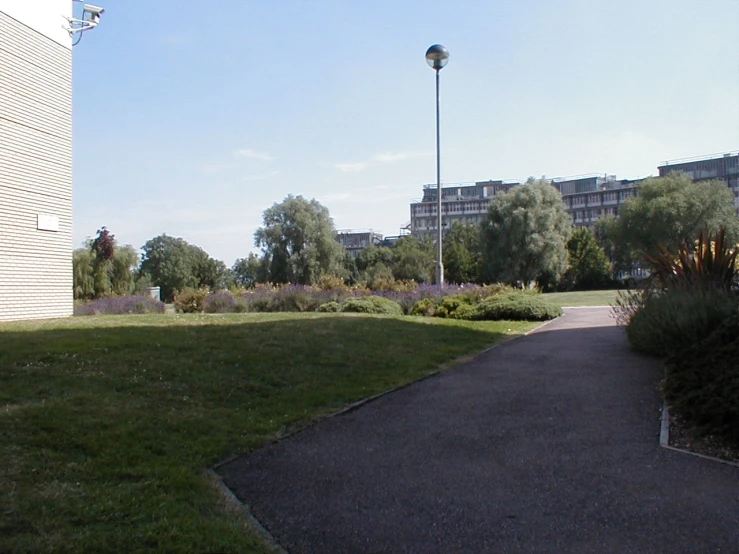 a pathway through a park next to trees and a large building