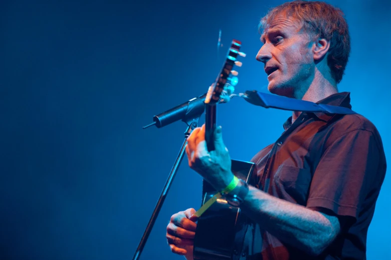 a man on stage with a guitar and a microphone