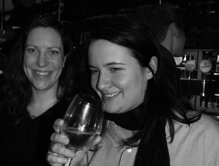 two smiling women holding up a wine glass