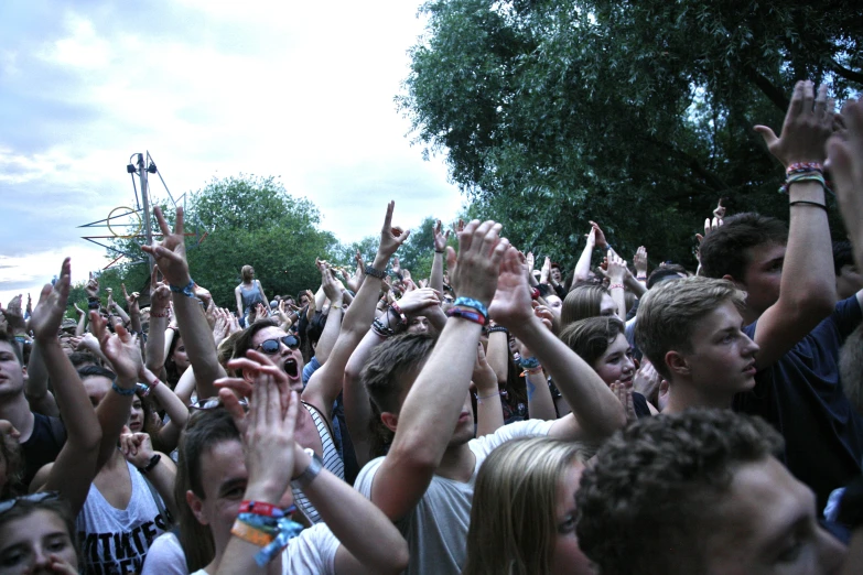 a large crowd holds up their hands to shake with the music on stage