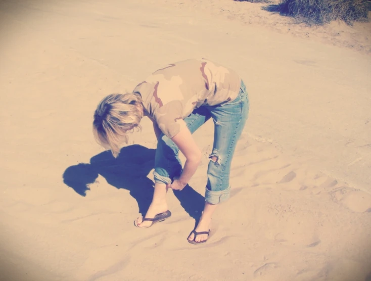 the woman is in the sand tying her shoes