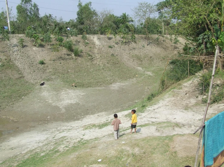 two people walking near the edge of a small hill