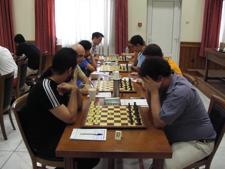 some people sitting at a table playing a game of chess