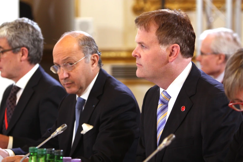 four men are sitting at a table looking off in the distance