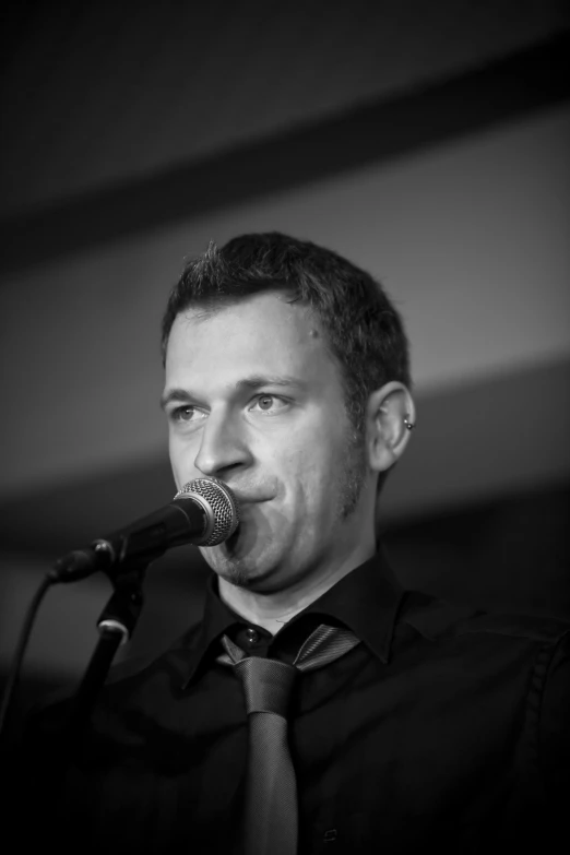 a man speaking into a microphone while holding a drink