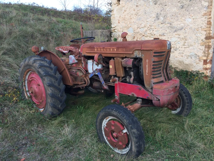 an old tractor sits near a building in the grass