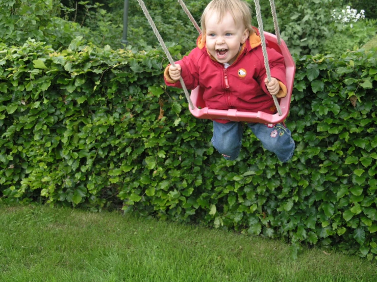 a toddler hanging on a pink toy swing