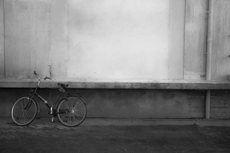 a bike leaning against a wall outside in black and white