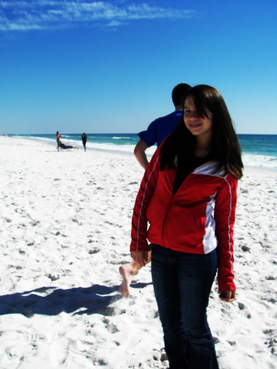 two people on the beach standing near the water