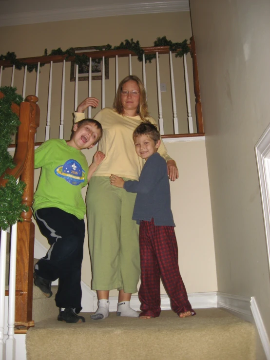 two women and one child stand on the stairs of a home