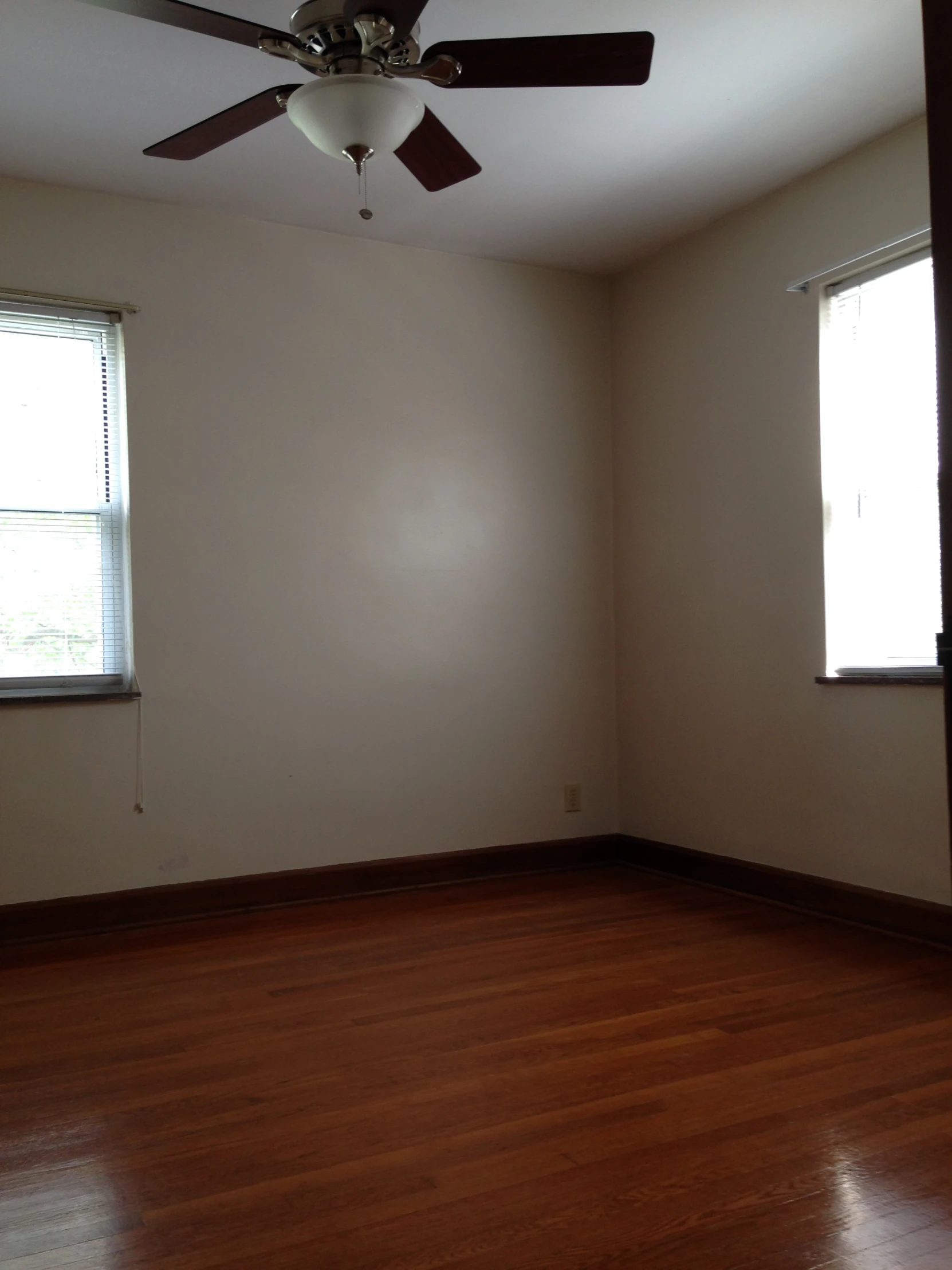 an empty room with wooden floors and ceiling fan