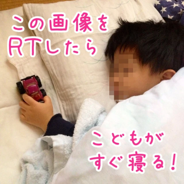 a little boy laying on a bed with a toy car