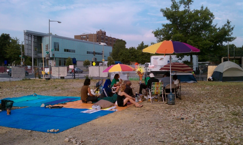 two women are sitting on the ground under an umbrella