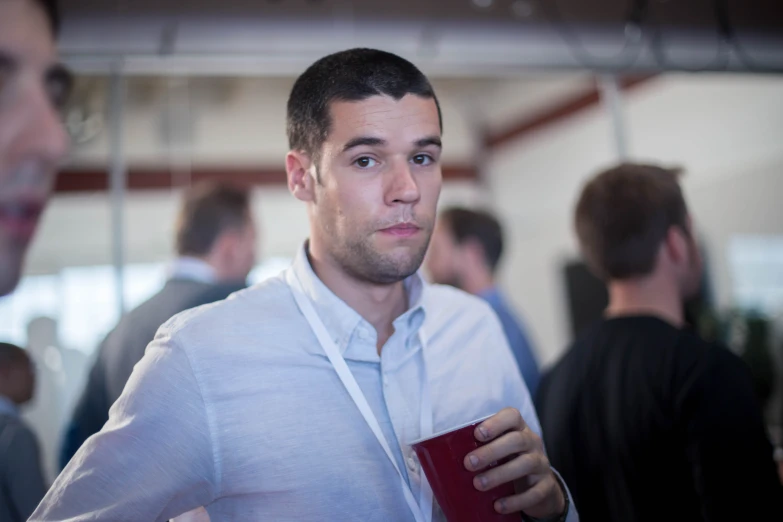 a man in white shirt drinking from red cup