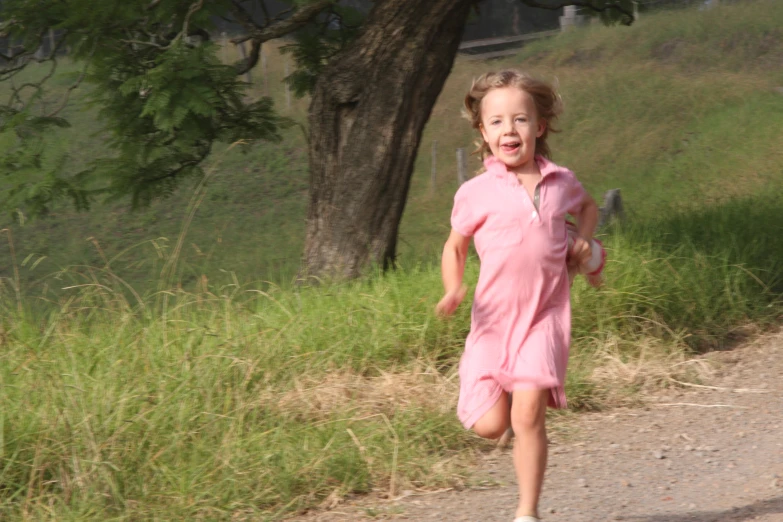 girl in a pink dress running along the road