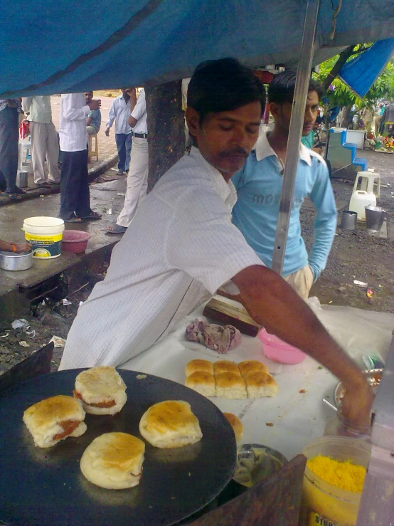 man cooking food on grill in open area