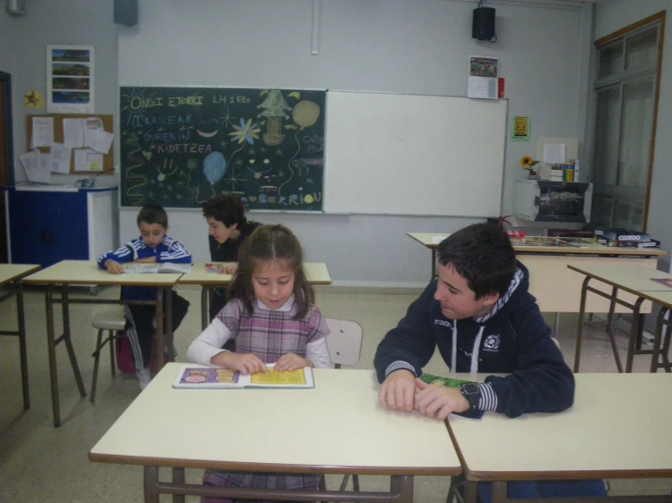 a man sitting at a desk with two children in front of him