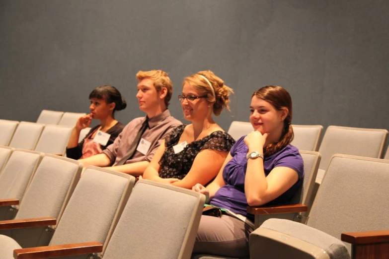 four people are sitting in the front row of a classroom