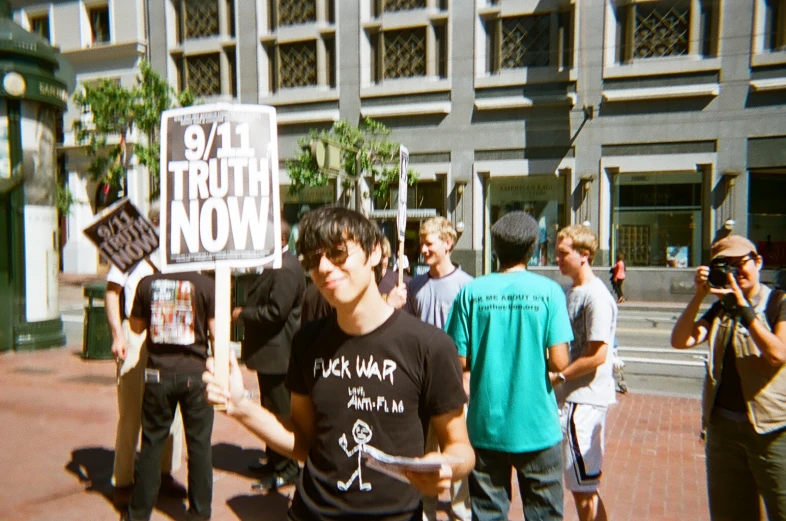 a group of young people standing around each other holding up a sign