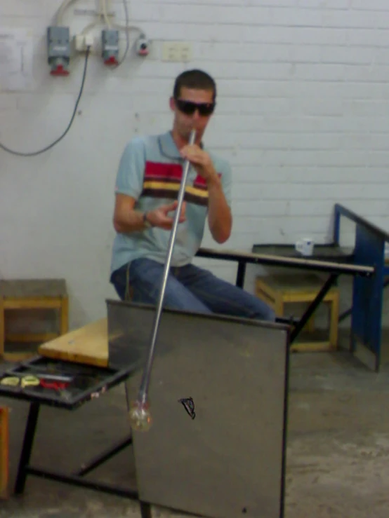 a man in a blue shirt and sunglasses holding a glass next to a television