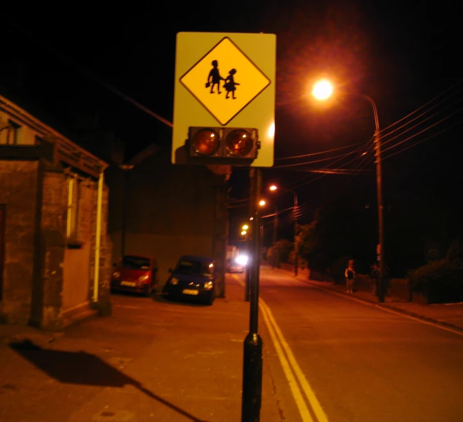 there is an intersection with two people crossing the street at night