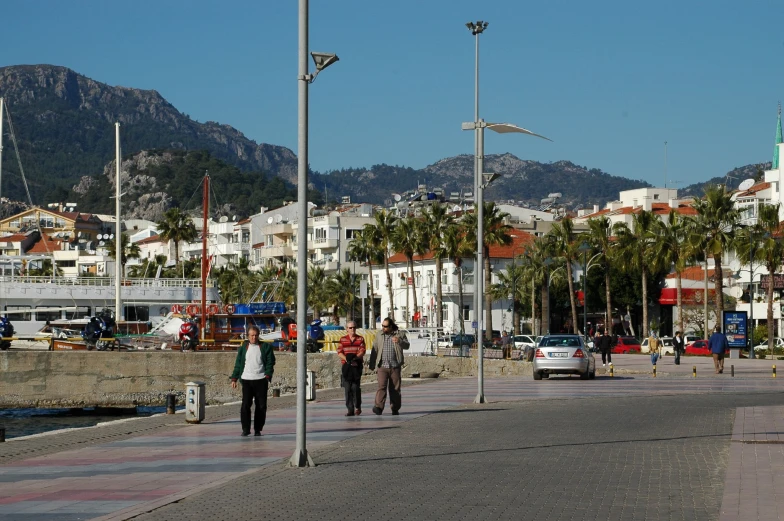 two people walking in the street near the water