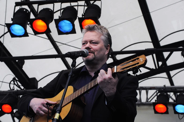 a man that is playing guitar near some lights