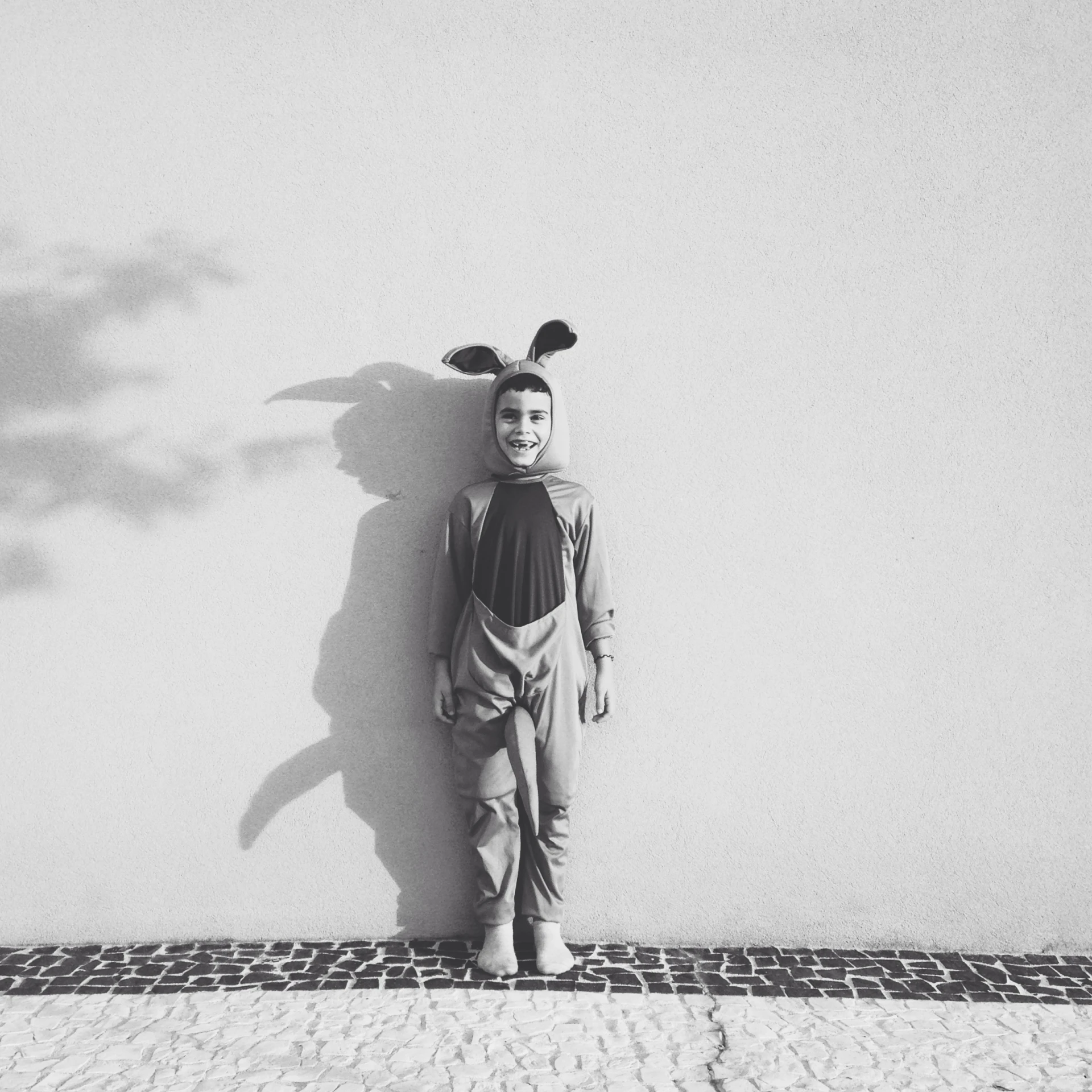 a little boy standing near a wall with some bunny ears