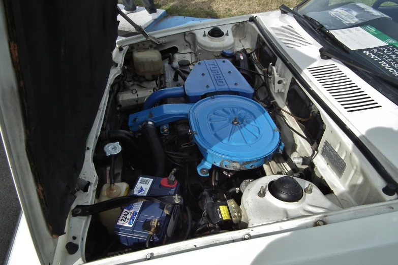 the hood of a van with a car engine and various items inside