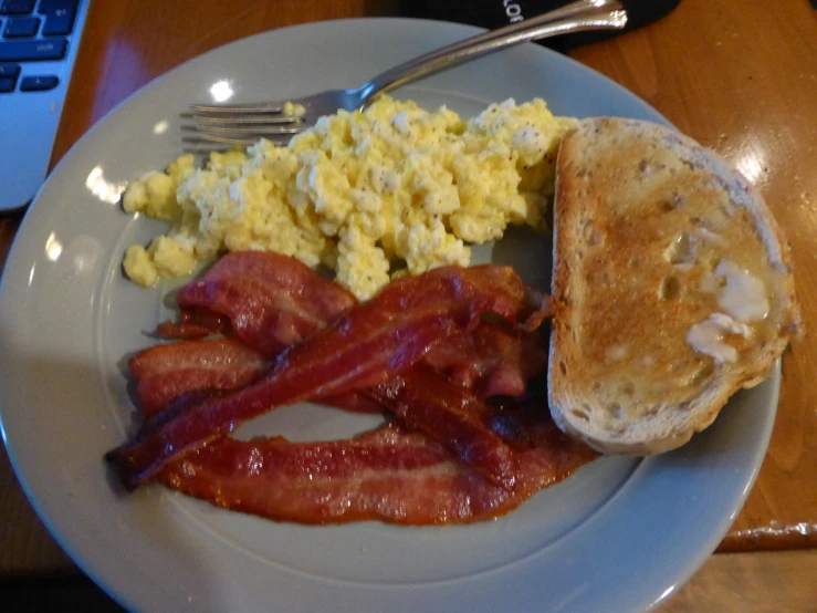 a plate of breakfast food with eggs, bacon, and toast