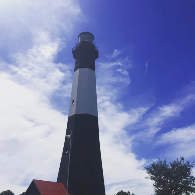 a light house on top of the ocean with blue skies and clouds