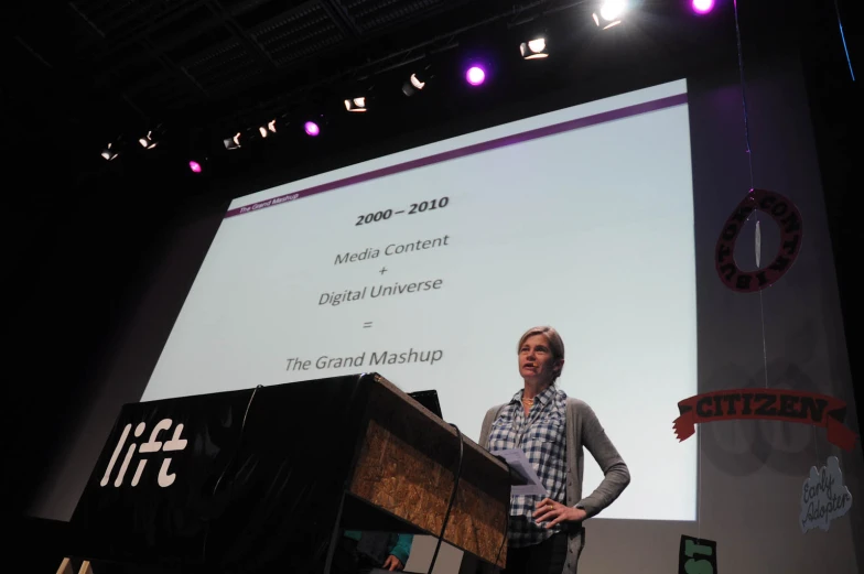 a man standing at a podium with a presentation screen